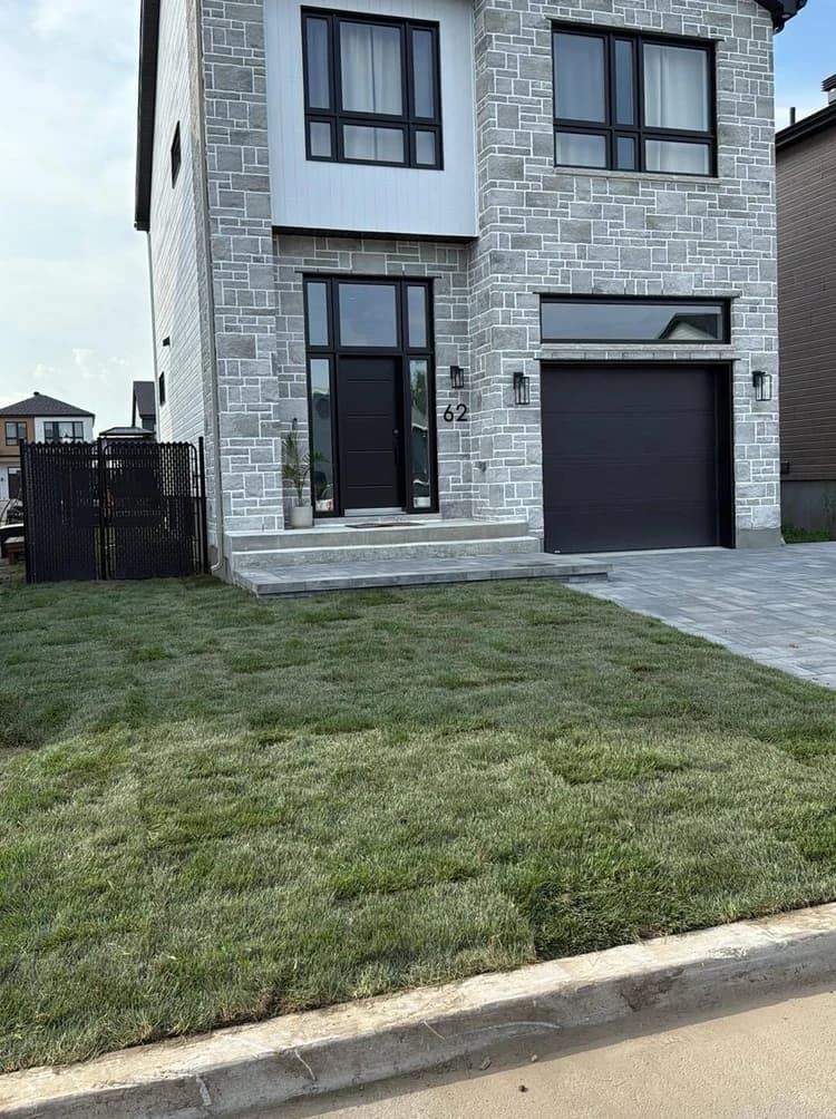 Pelouse neuve devant une maison de pierre