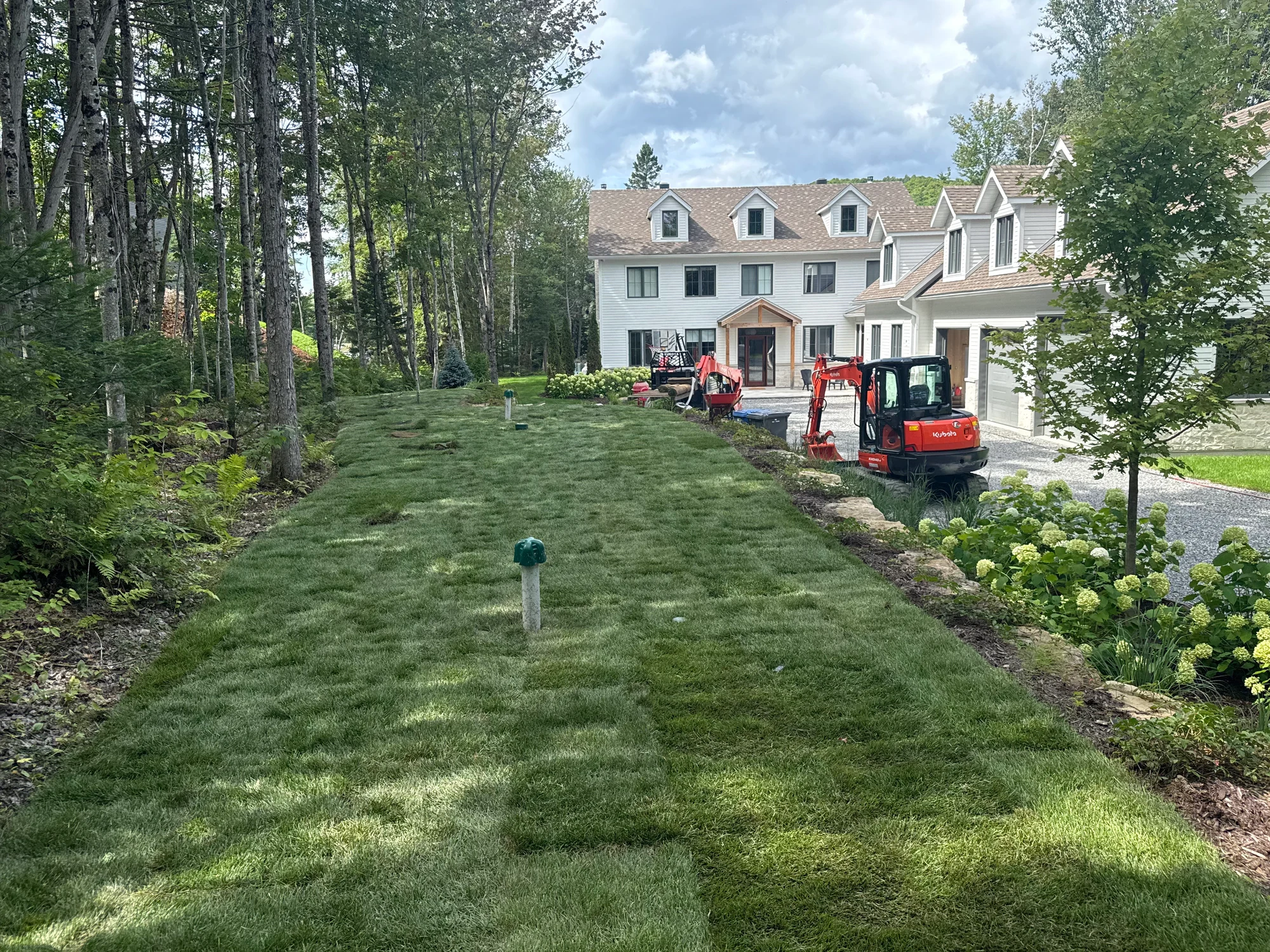 Grande propriété dont le terrain vient d'être recouvert de tourbe fraîche, machines de TerraCare au fond.